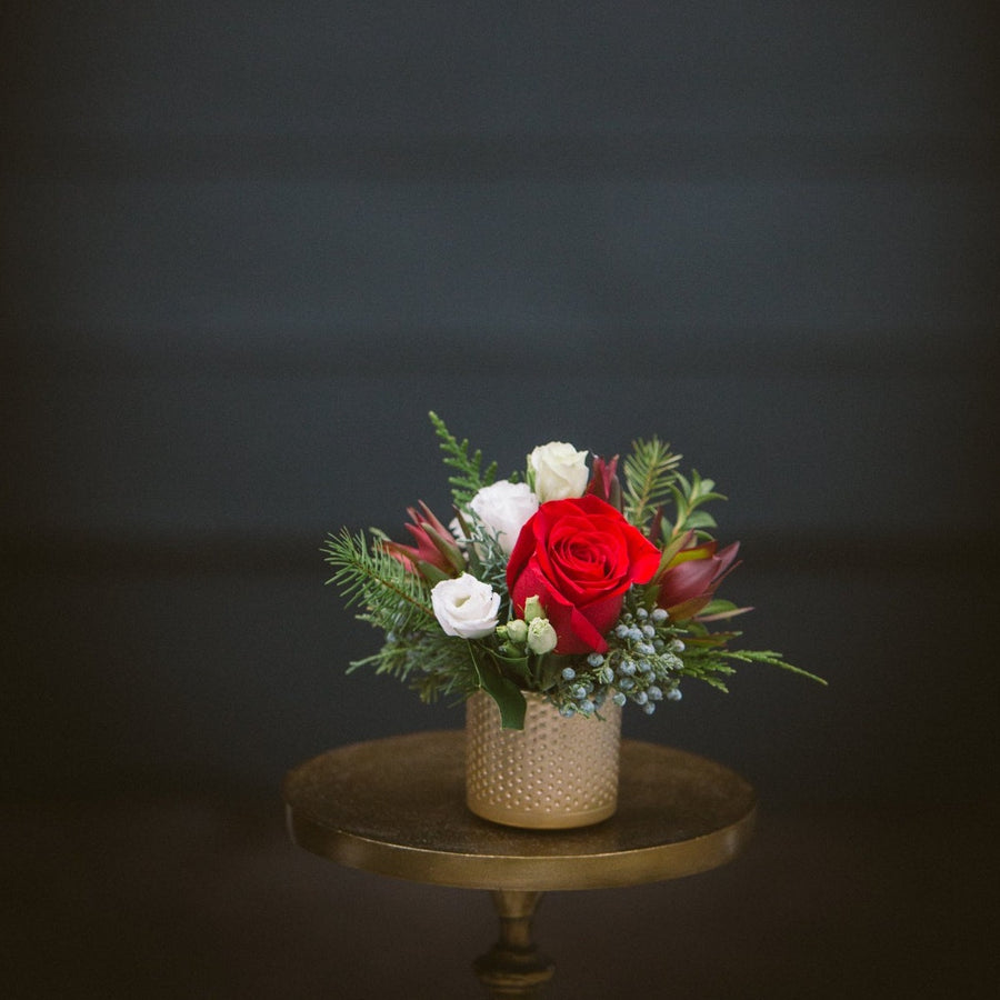 small gold dimple vase with seasonal winter greens roses and  lisianthus