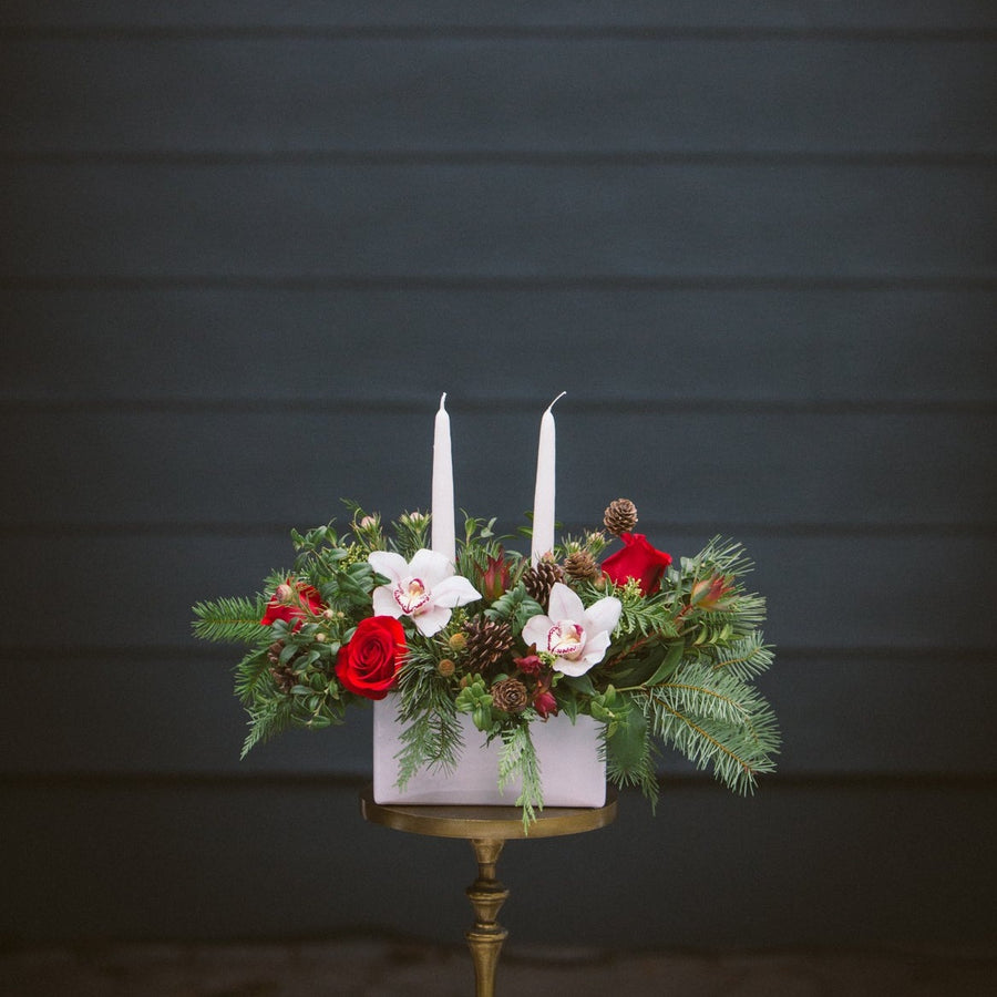 two candle table centerpice in white container with red and white flowers