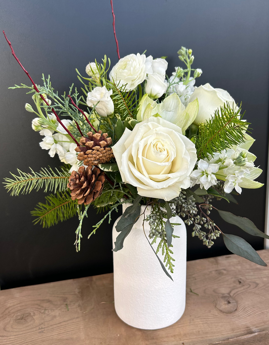 Large white and green winter arrangement in white milk jug.
